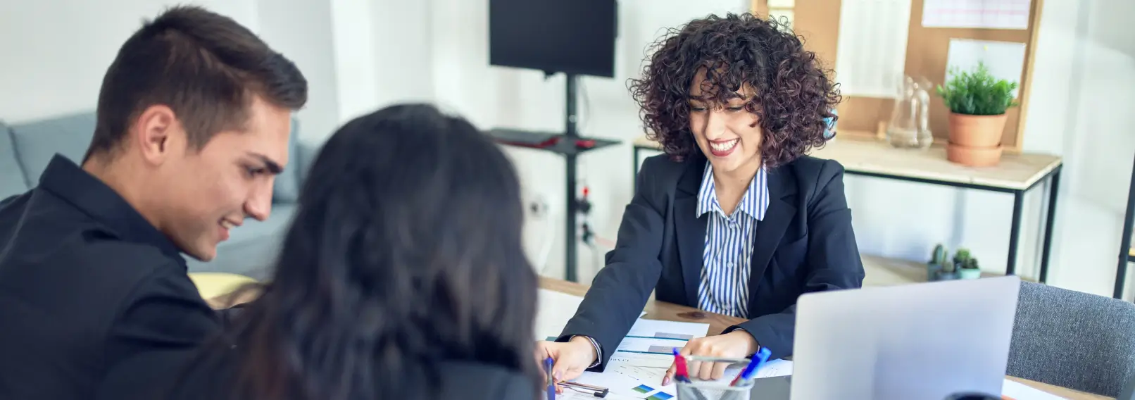 Happy banker helping a couple sign finance papers.