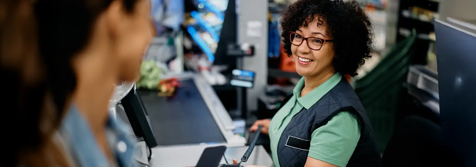 A smiling cashier helping a customer pay with their phone.