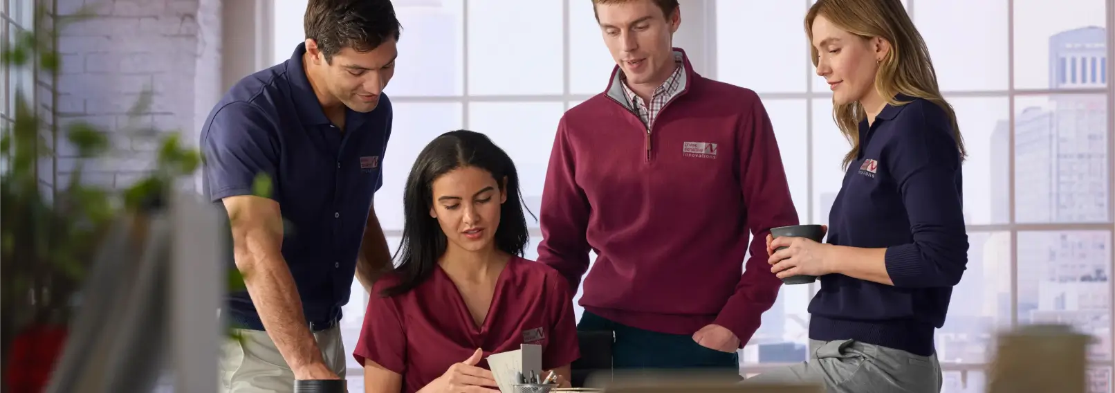 Coworkers in coordinated branded apparel, including navy polos and a burgundy quarter-zip.