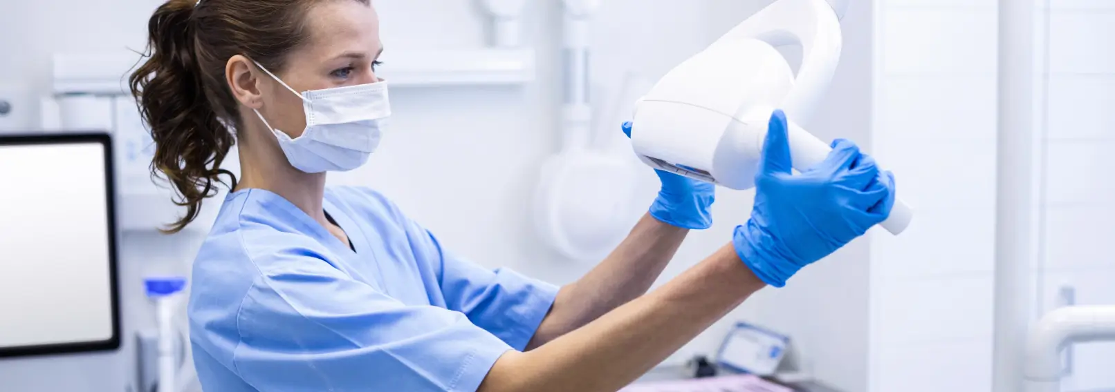 Dental worker wearing a mask and gloves adjusting a light.
