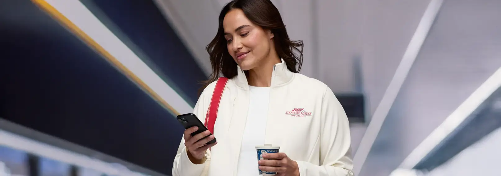 A remote employee in a branded quarter-zip pullover checking her phone