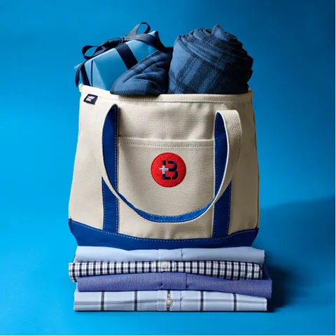 A canvas tote with blue accents filled with gifts.