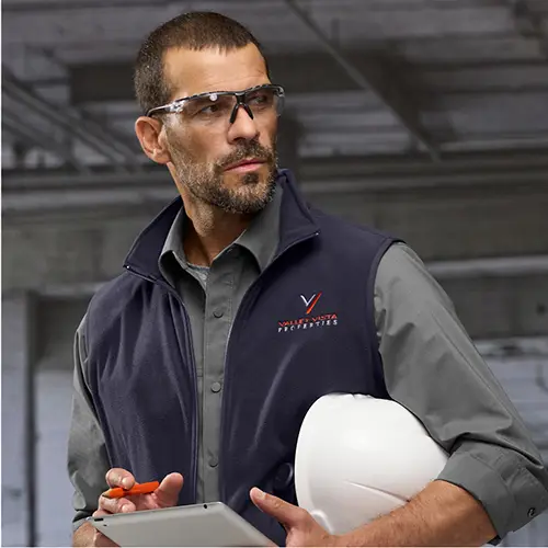 Construction crew manager holding a hard hat helmet.