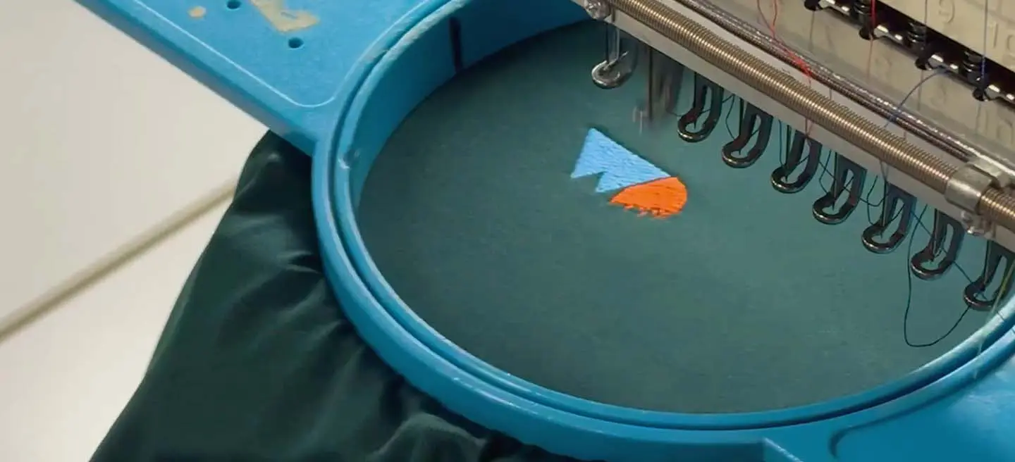 An embroidery machine stitching a logo on clothing.