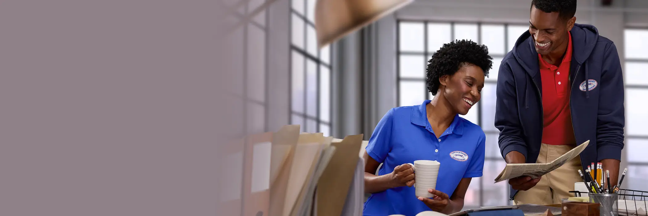 Two employees reading a newspaper together in an office.