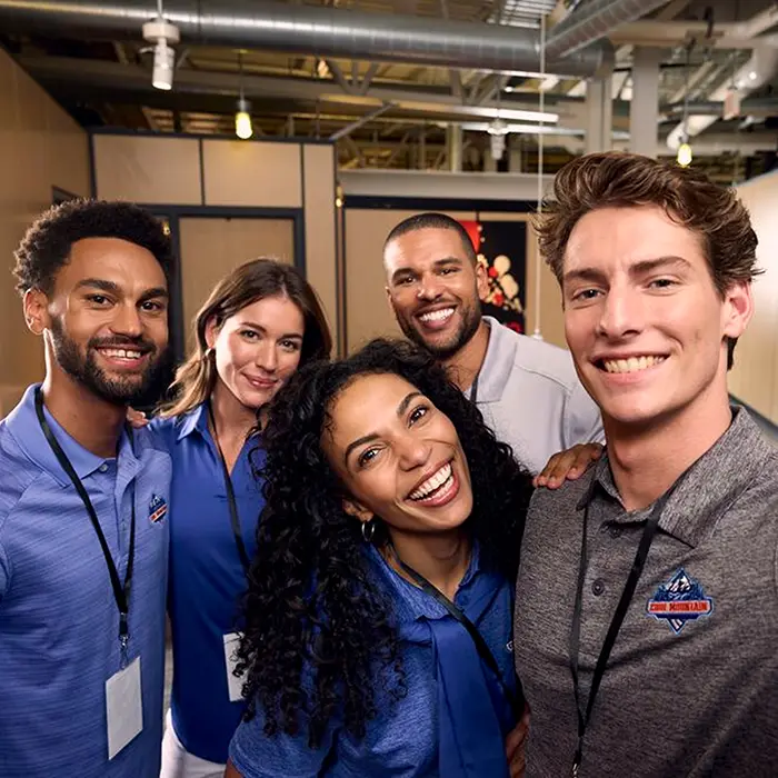 A smiling team of employees wearing branded apparel for their organization.