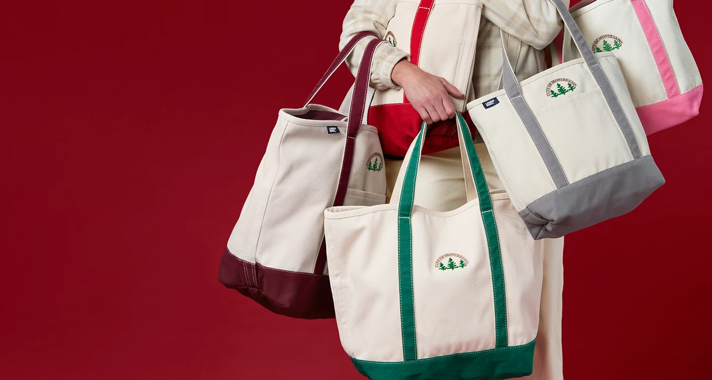 Person holding monogrammed canvas totes in assorted colors and sizes