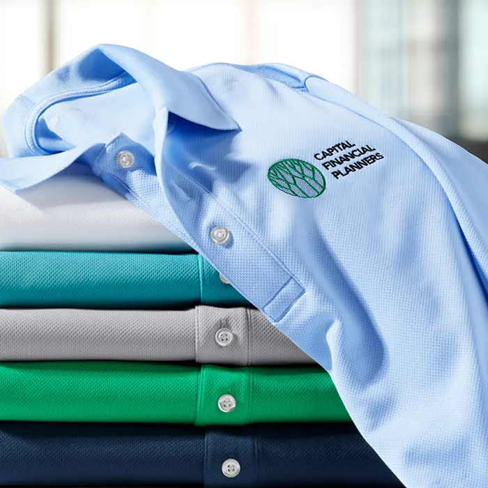 A stack of cool toned polo shirts with custom logo emrboidery.