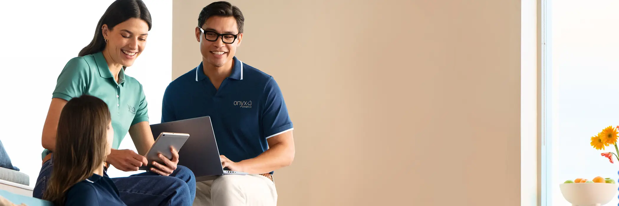 Three employees collaborating on laptops and tablets.